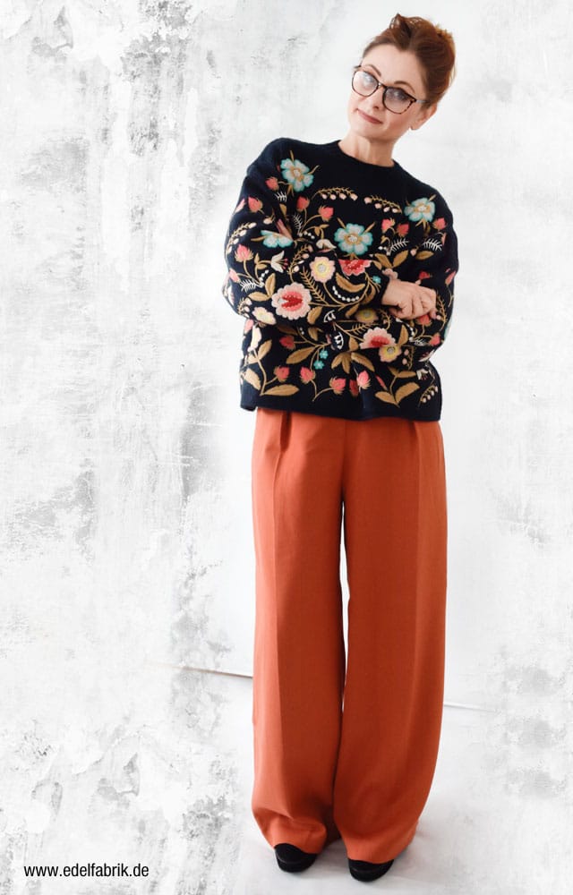 schwarzer Pullover mit üppiger Blumenstickerei zu oranger Marlene Hose