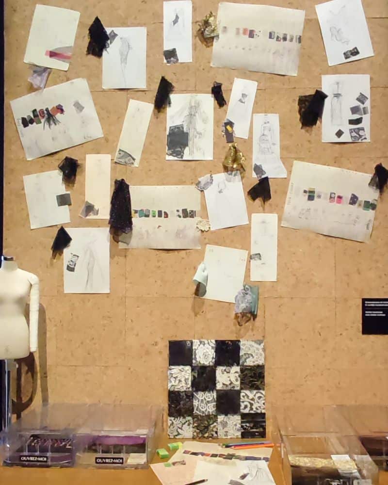 Der Schreibtisch von Yves Saint Laurent mit zahlreichen Skizzen und Stoffmustern die an der Rückwand angeheftet sind.