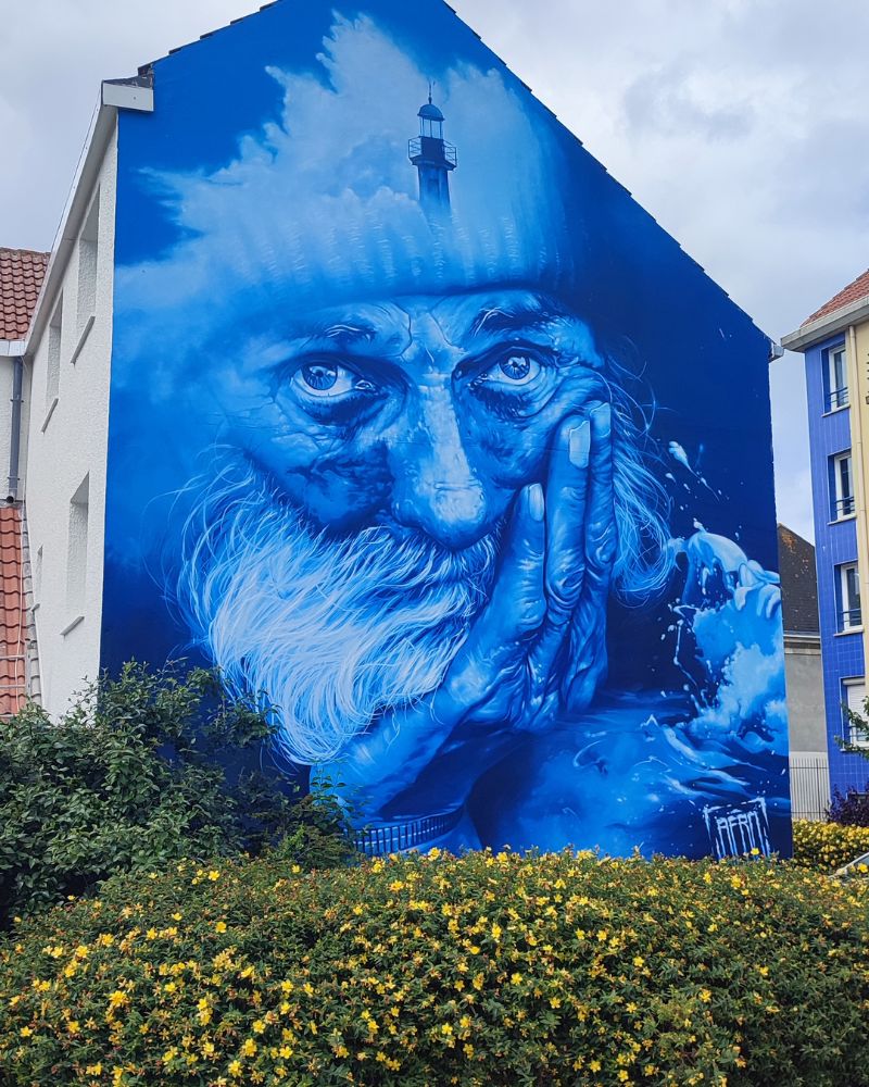 Ein Murral eines alten Mannes der aussieht wie ein Fischer ganz in Blau gehalten. Streetart in Calais.