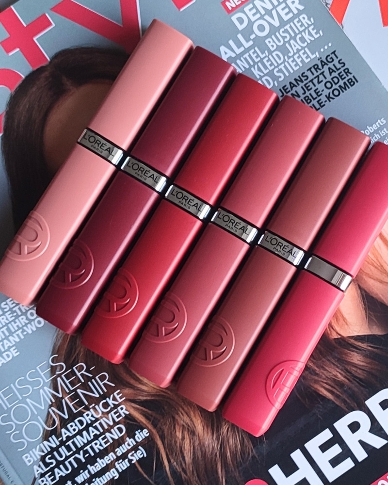 Verschiedene Farben des Infaillible Matte Resistance Lippenstiftes liegen geschlossen und nebeneinander aufgereiht auf einem Modemagazin.