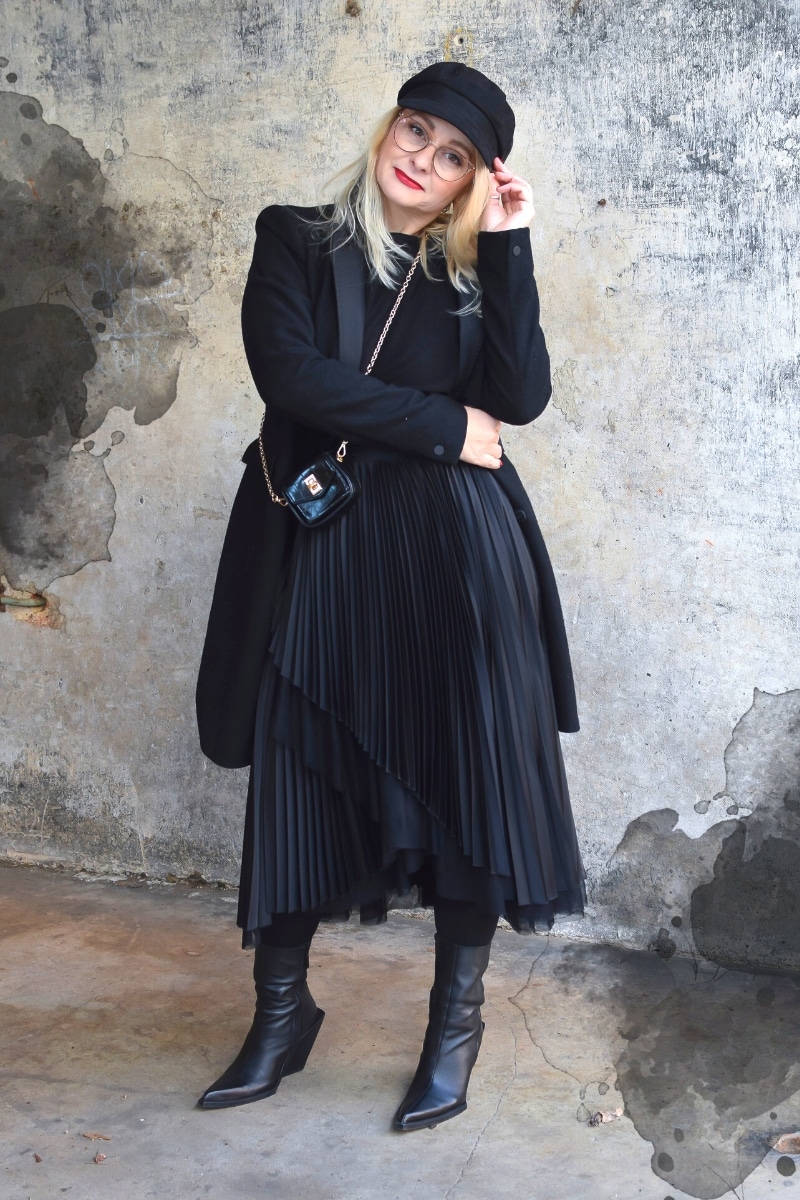 Eine blonde Frau trägt ein Outfit komplett in Schwarz.
