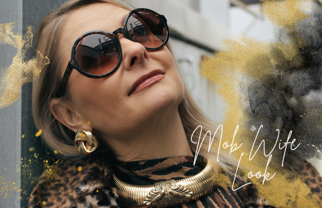 Portrait einer Frau mit großer Sonnenbrille und Goldschmuck in Mob Wife Look Ästhetik