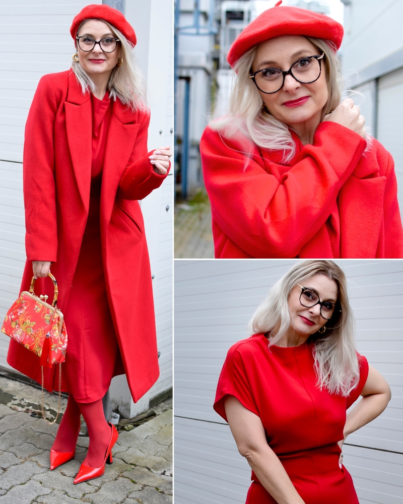 Eine blonde Frau trägt ein Outfit komplett in Rot. Ein Mantel, ein Kleid, eine Mütze, eine Strumpfhose und Pumps mit hohem Absatz. Dazu trägt sie eine rote Handtasche.