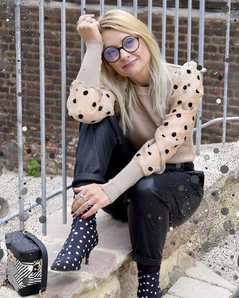 Frau trägt Punktemuster im Herbst 2026 mit schwarzer Lederhose und Pullover in Beige mit schwazen Punkten und gepunkteten Stiefeletten